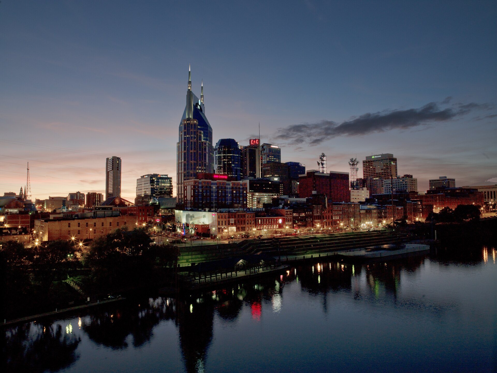 Downtown Nashville at dusk from across the Cumberland River, with the AT&T Building lit against the sunset.